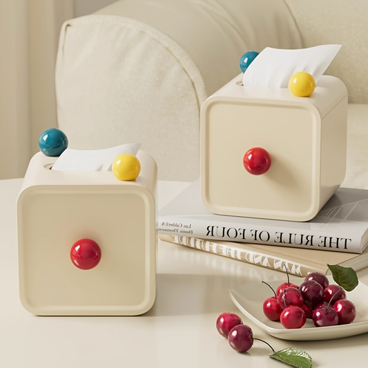 A chic cream-colored tissue box decorated with colorful little balls.